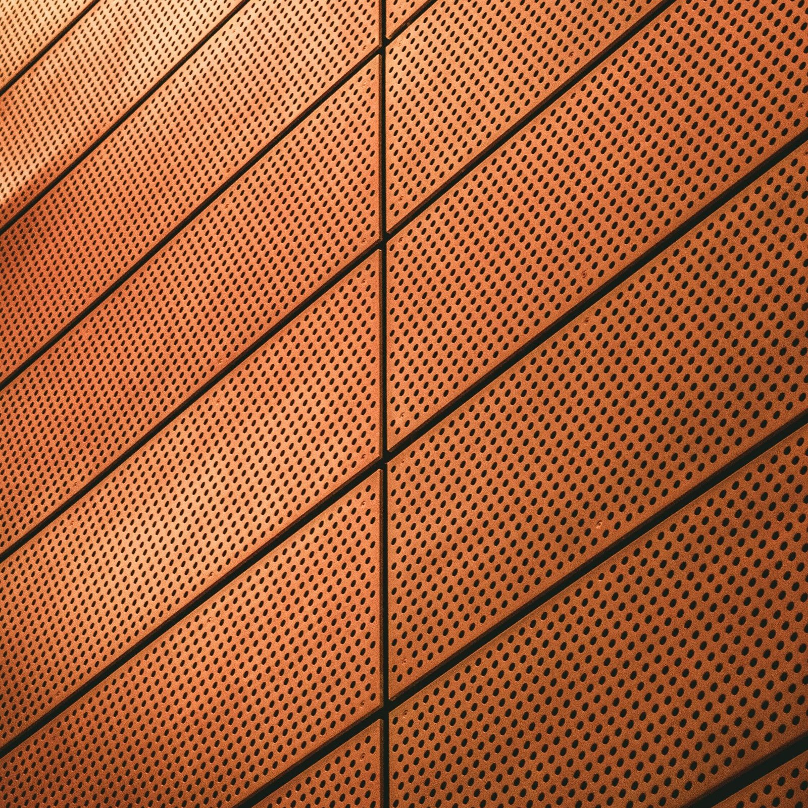 Abstract view of a modern metal wall with geometric patterns and warm lighting.